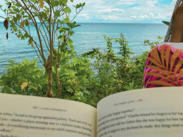 A mother spending me-time, prioritizing self-Care by reading a book on a hammock by the beach