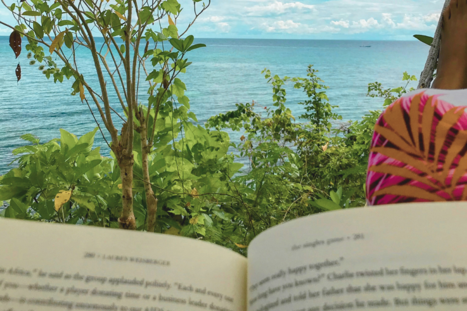 A mother spending me-time, prioritizing self-Care by reading a book on a hammock by the beach