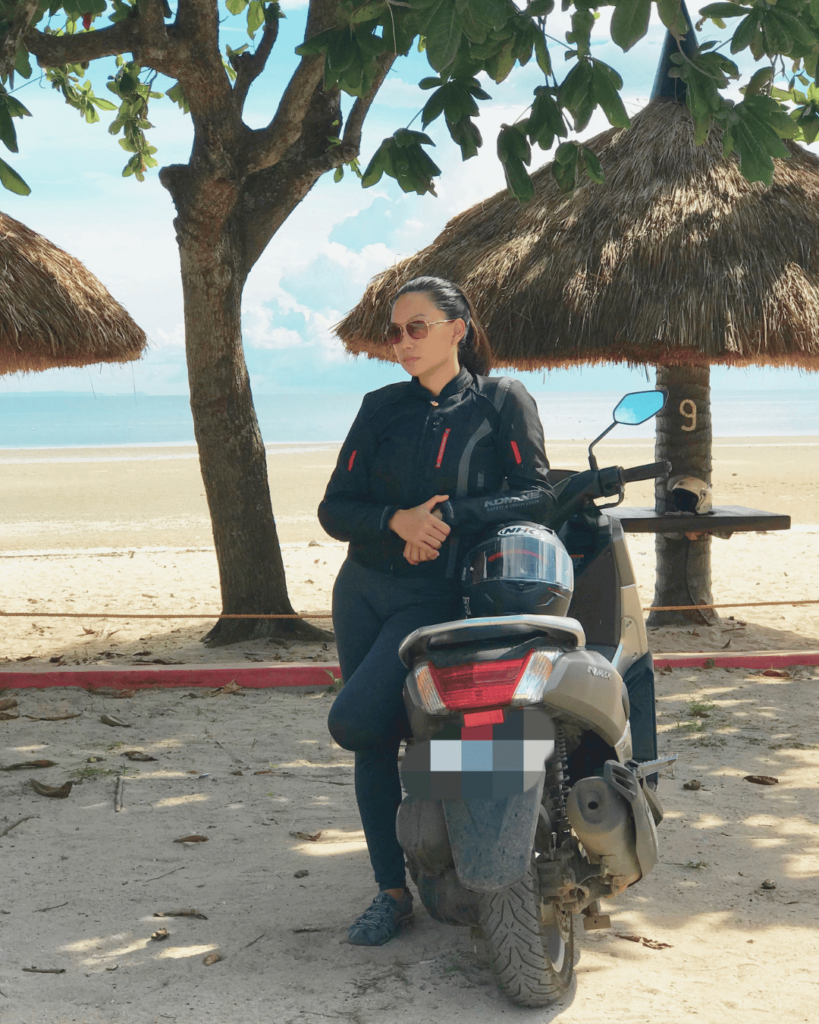 Girl on a motorcycle with a bikers outfit with a beach background