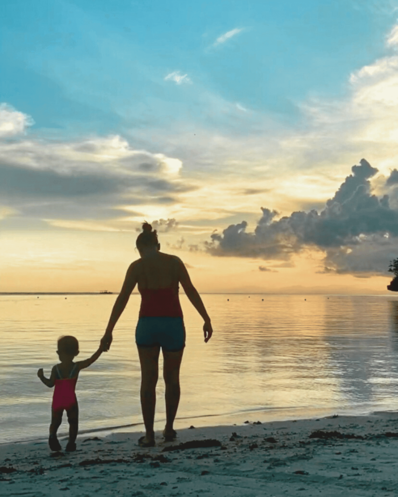 Mother and Toddler on the beach holding hands during sunset