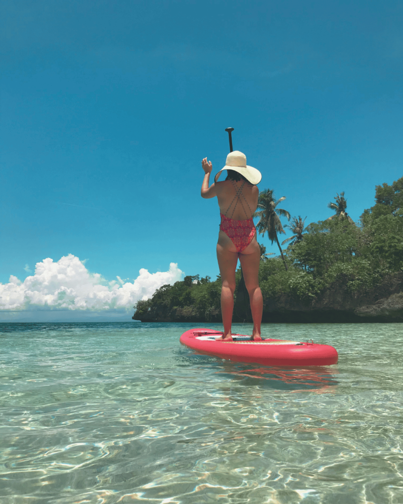 Girl on a Stand Up Paddle on the beach during a beautiful, sunny day with turquoise blue water under a blue sky