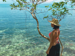 Lady leaning on a tree overlooking a serene and peaceful view of the ocean