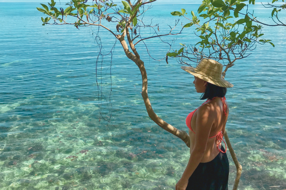 Lady leaning on a tree overlooking a serene and peaceful view of the ocean