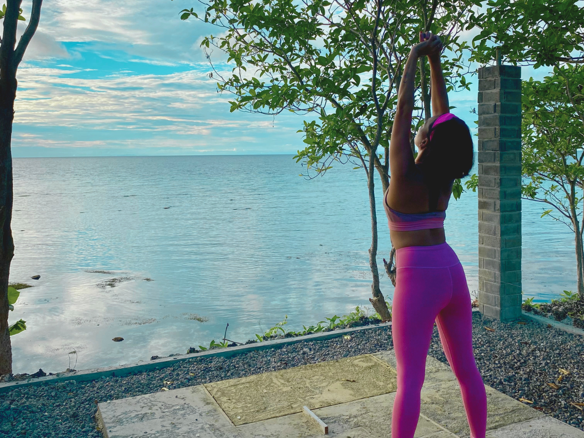 A woman in workout clothes stretching in the morning as a way to improve physical health as a mom
