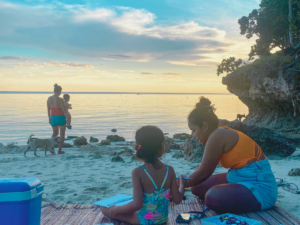 Family and friends having a picnic at the beach while waiting for sunset