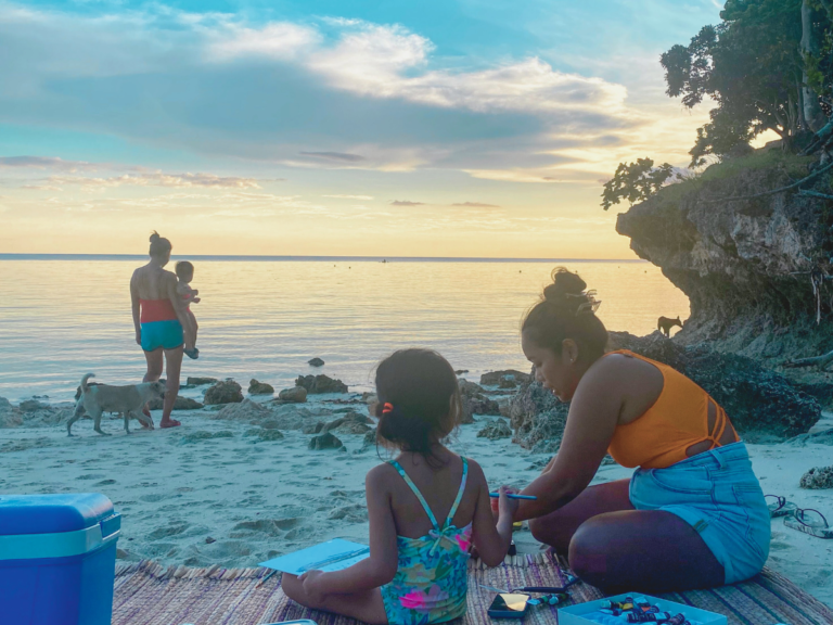 Family and friends having a picnic at the beach while waiting for sunset