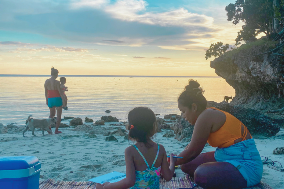 Family and friends having a picnic at the beach while waiting for sunset