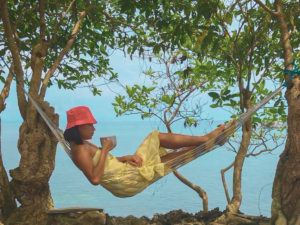 Woman drinking coffee on a hammock overlooking the ocean enjoying some me-time