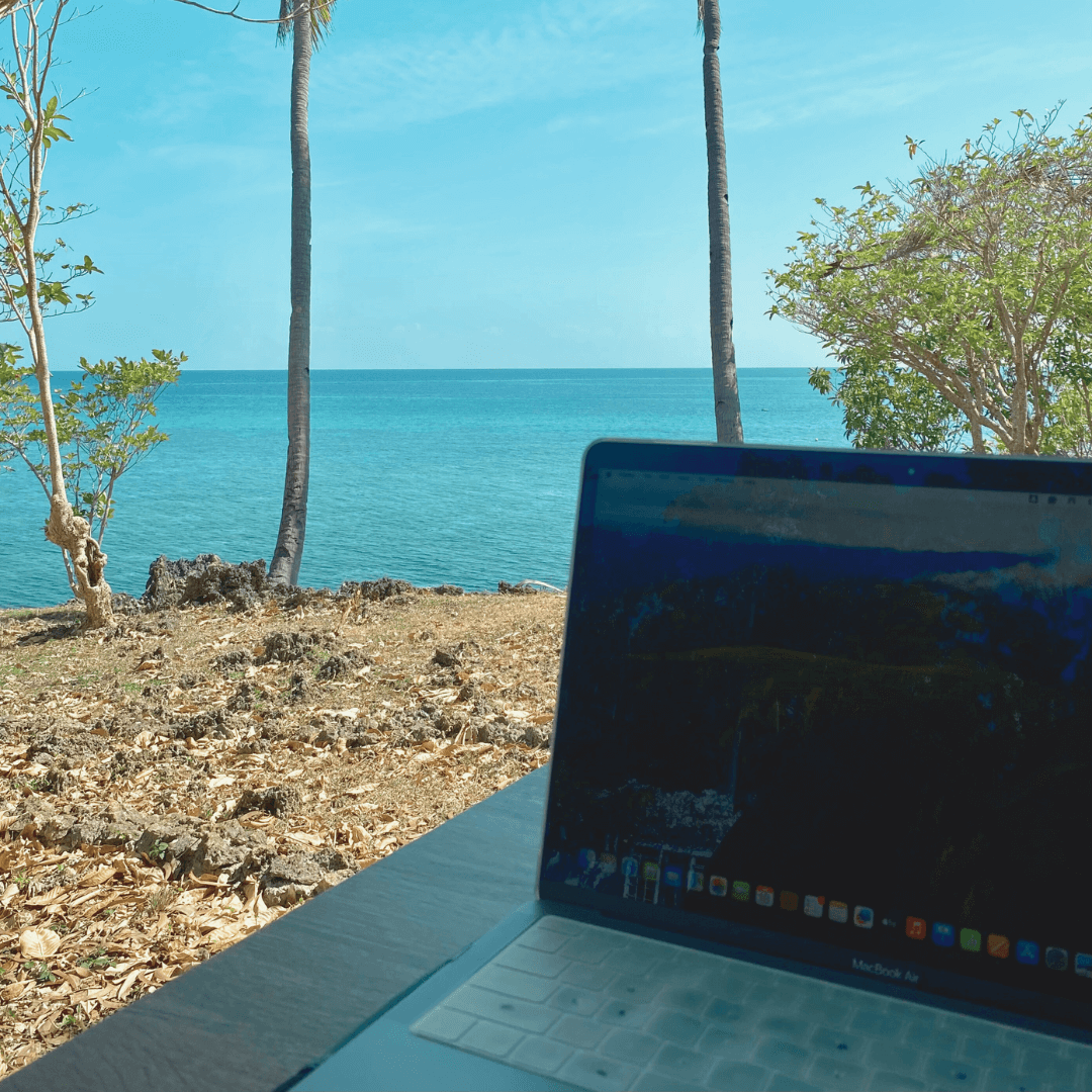 An open laptop on a table with the background of the ocean