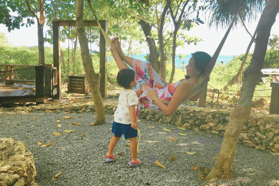 A mother relaxing on a hammock under the trees, playing with her daughter, reflecting on the journey of how she lost herself and found peace in nature.