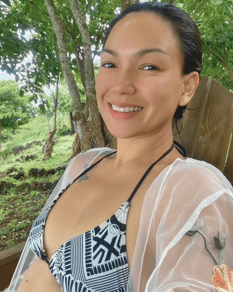 mom wearing a swimsuit with a cover-up sitting on a chair smiling surrounded by nature