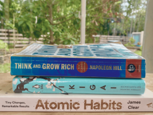 3 Must-Read Wellness Books for Mothers stacked on the table with a background of nature