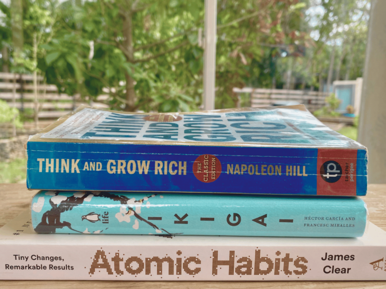 3 Must-Read Wellness Books for Mothers stacked on the table with a background of nature