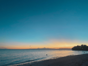 A breathtaking sunset by the beach, with golden-yellow and orange hues blending across the sky. A soft ray of light stretches over the horizon, casting a warm glow on the water—a serene reminder of life’s beauty and your own worthiness to experience and embrace it fully.