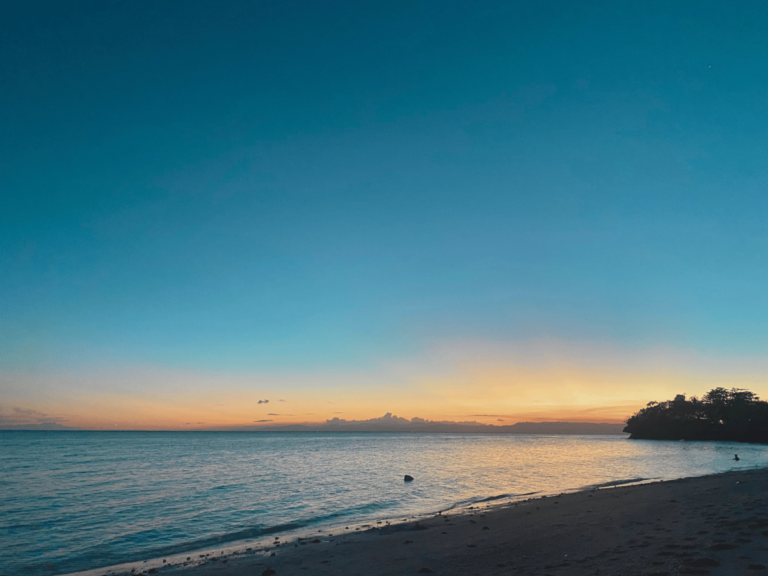 A breathtaking sunset by the beach, with golden-yellow and orange hues blending across the sky. A soft ray of light stretches over the horizon, casting a warm glow on the water—a serene reminder of life’s beauty and your own worthiness to experience and embrace it fully.