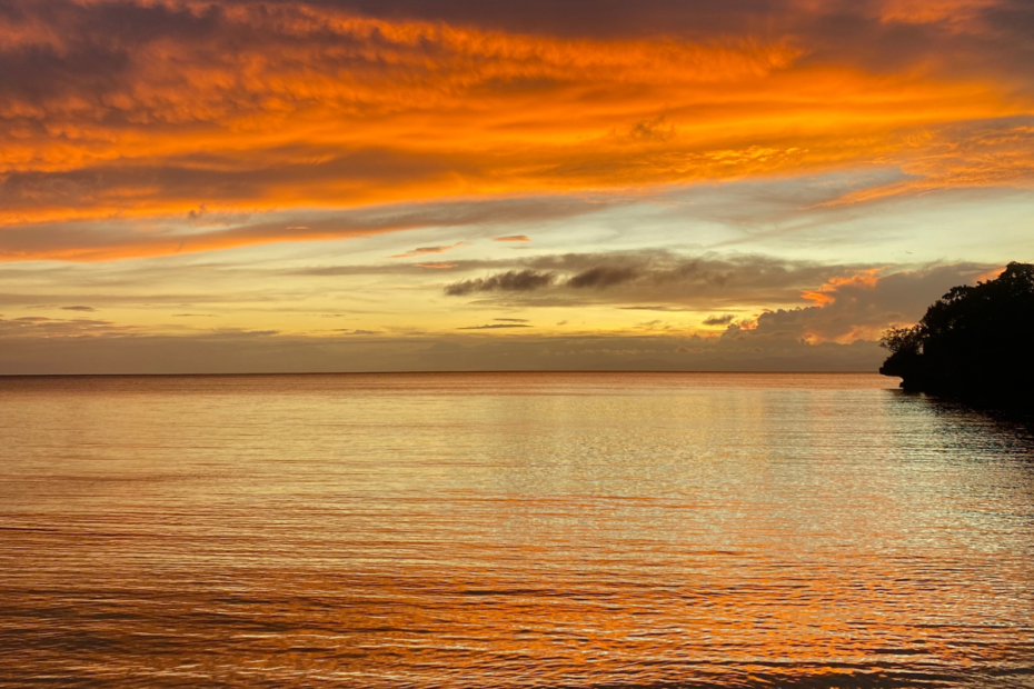 A breathtaking sunset over the ocean, with vibrant orange hues painting the sky and reflecting beautifully on the calm water below—a perfect moment for new year reflection.