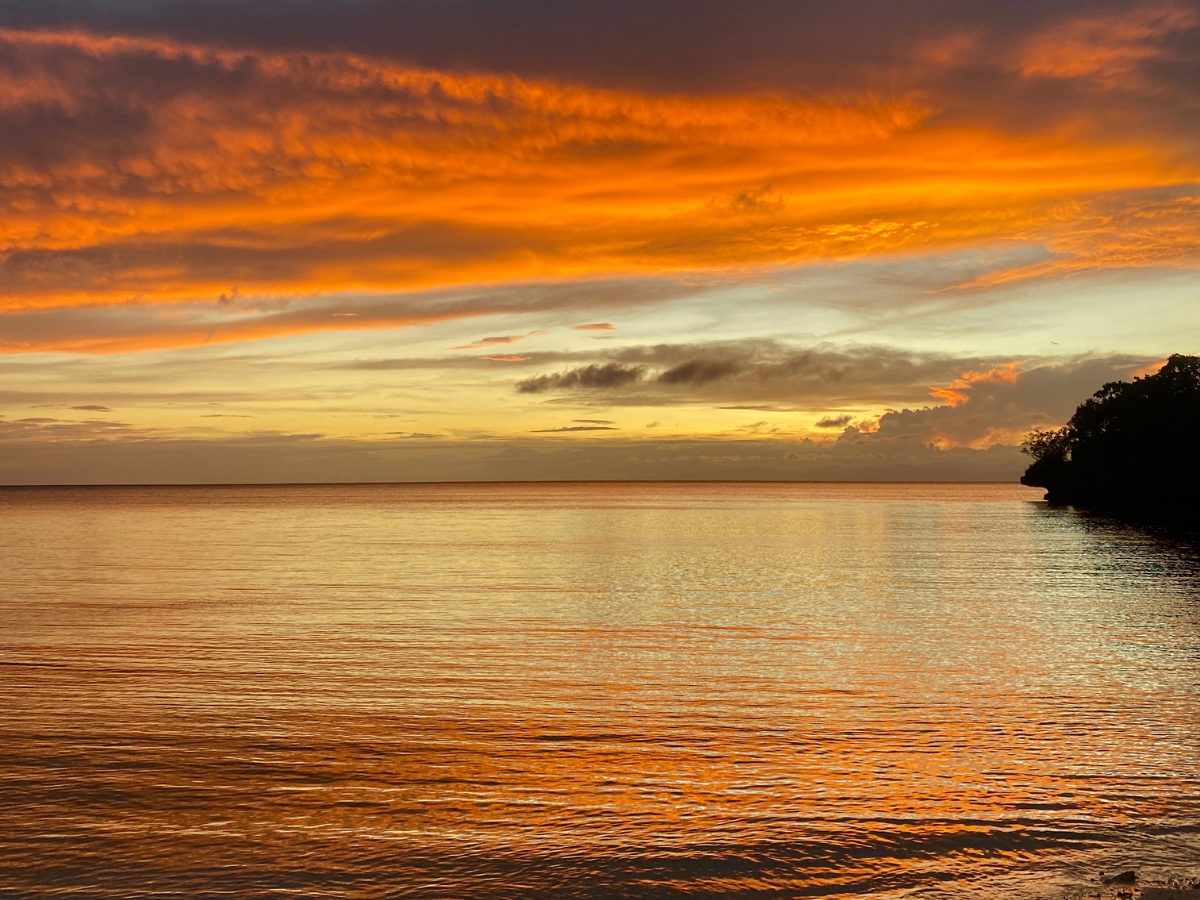 A breathtaking sunset over the ocean, with vibrant orange hues painting the sky and reflecting beautifully on the calm water below—a perfect moment for new year reflection.