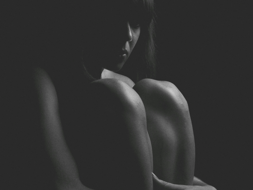 A woman sitting in the darkness going through postpartum recovering from birth