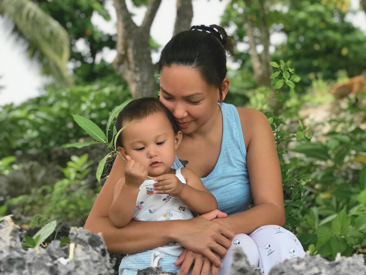 A mom sits with her toddler, looking out at the ocean, surrounded by nature. She takes a quiet moment for herself, recovering from birth and embracing the journey of motherhood.
