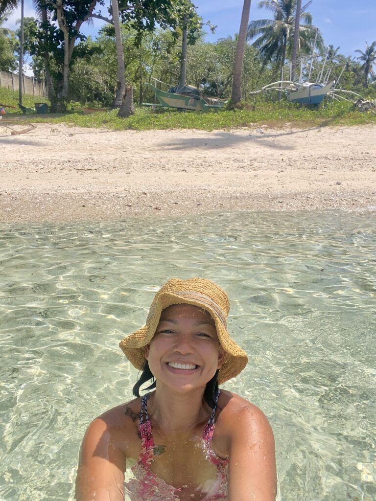 A mom smiling brightly enjoying the beach practicing self-care for moms