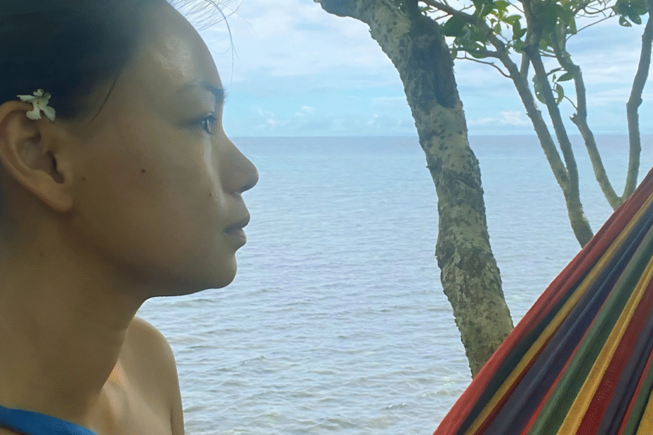A woman wanting to be More than just a mom sitting on a hammock on a cliff with a view of the ocean.