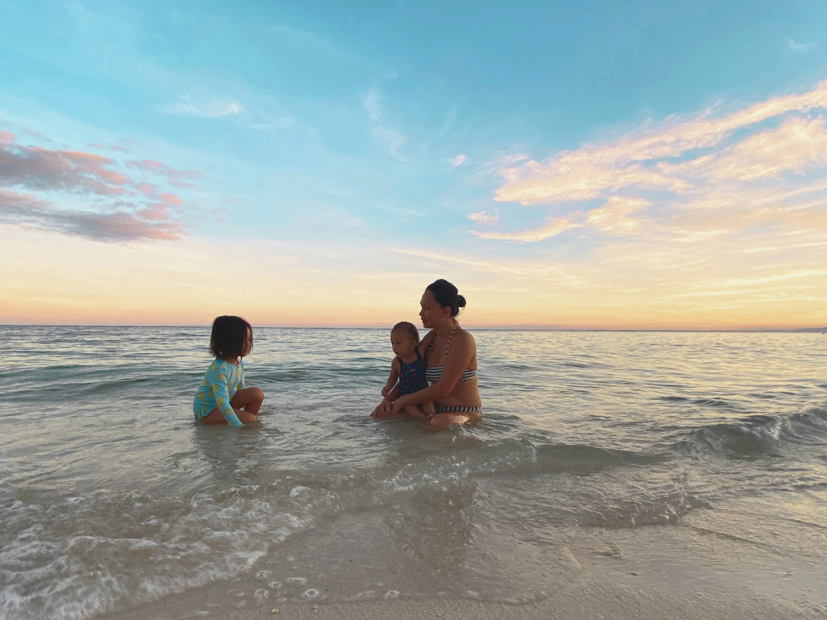 Giving up your career to be a stay-at-home mom can look like this: a mom with her two daughters enjoying the beach at sunset