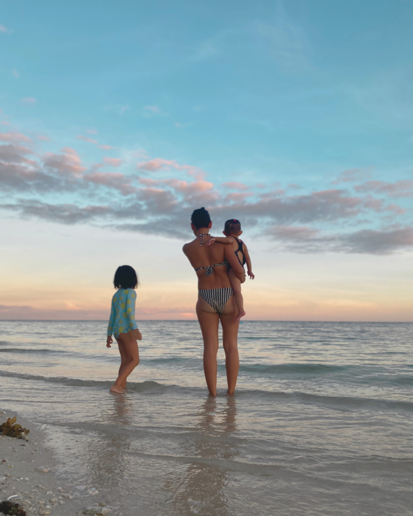 A mom enjoying the sunset with her two daughters at the beach