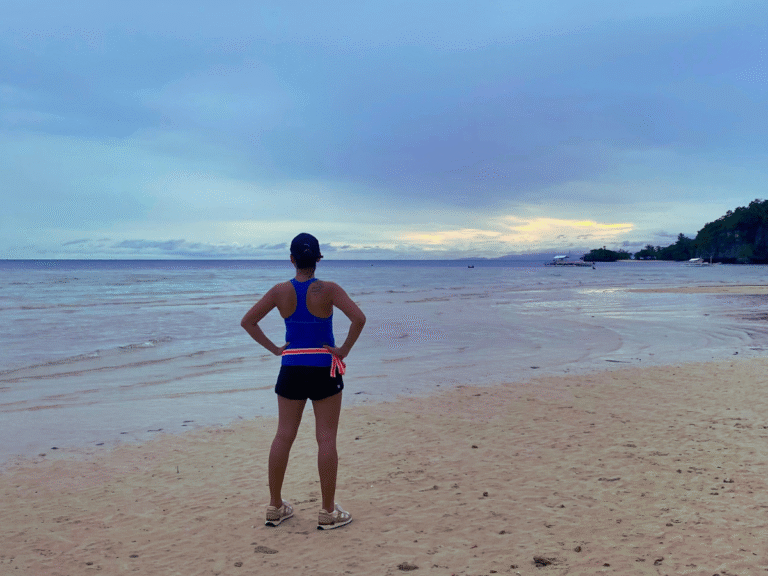 Ambitious moms represented by a woman doing a power pose at sunset after a run, showing strength, clarity, and identity beyond motherhood.