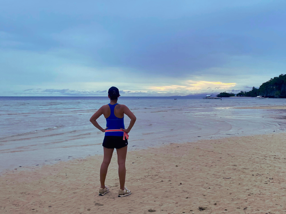 Ambitious moms represented by a woman doing a power pose at sunset after a run, showing strength, clarity, and identity beyond motherhood.