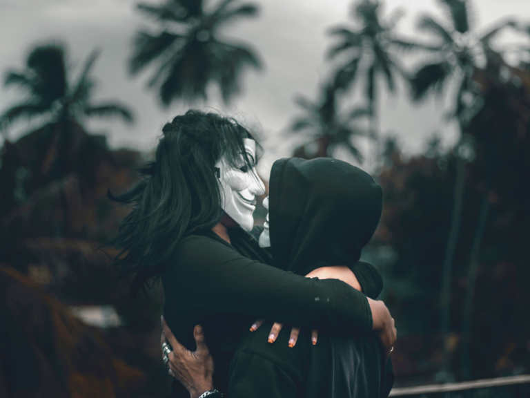A couple embracing with masks on, representing subtle toxic relationship red flags hidden beneath affection and intimacy.