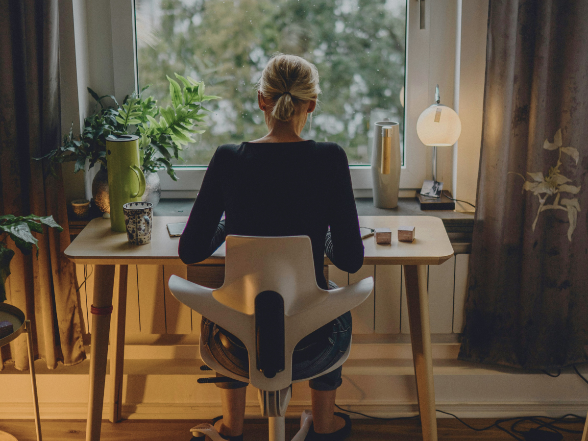 A mom sitting by the window working at home returning to work after motherhood