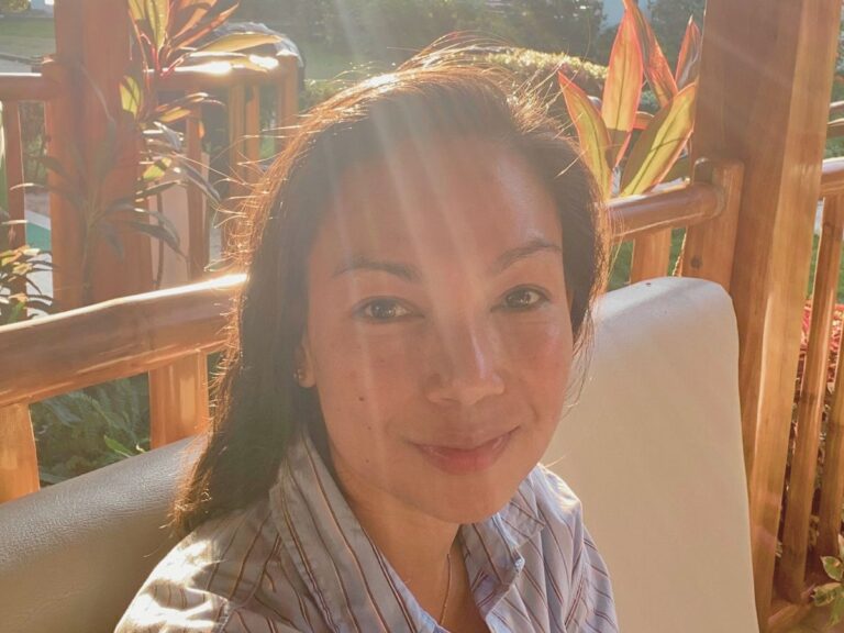 A smiling mom enjoying a peaceful sunset during her midlife awakening journey.