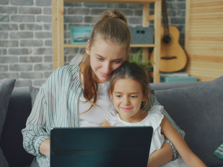 Mother using a laptop with her daughter while learning how to restart her career after motherhood