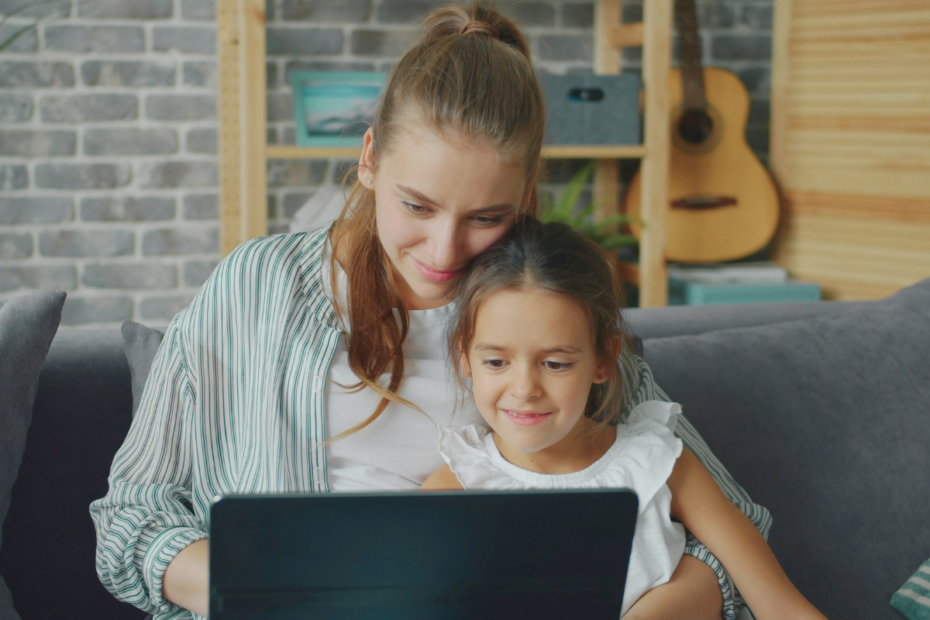 Mother using a laptop with her daughter while learning how to restart her career after motherhood